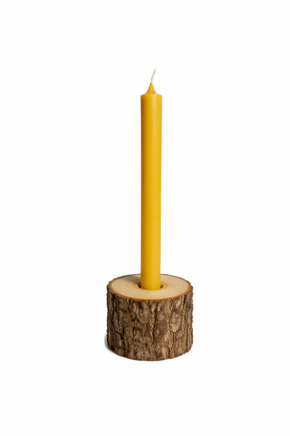 Tall yellow handmade beeswax candle in wooden holder with white background