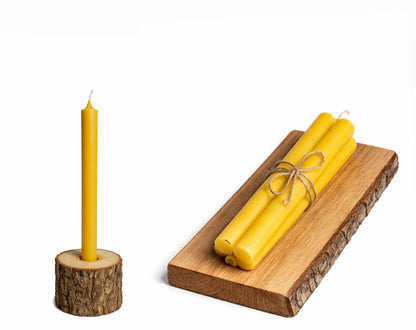 Yellow tall handmade beeswax candles with a wooden holder and tray on a white background