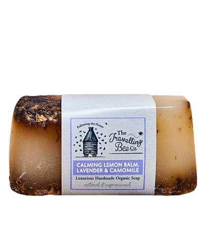 Bar of handmade soap with a label from The Travelling Bee Co on a white background