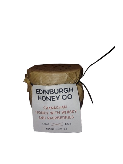 Jar of Edinburgh Honey Co. cranachan honey with whisky and raspberries on a white background