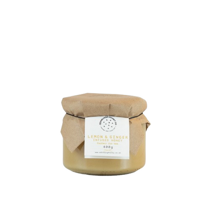 Jar of lemon and ginger infused honey with a label on a white background