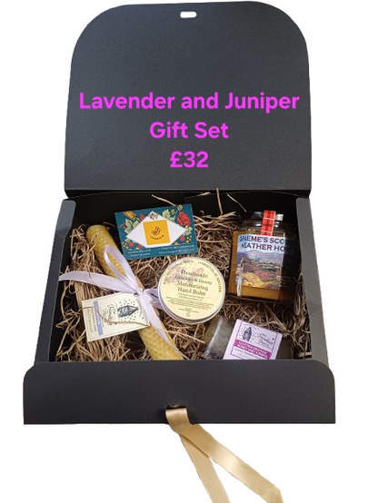 Gift set with lavender and juniper theme, including a candle and other items, displayed in a black box.