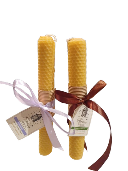 Two wrapped honeycomb beeswax candles with ribbons and labels on a white background
