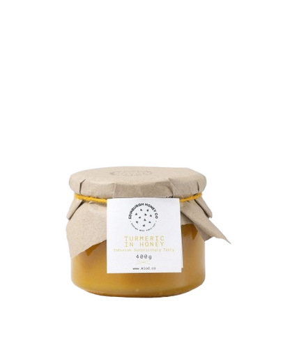 Jar of turmeric  honey with a beige lid and a label on a white background